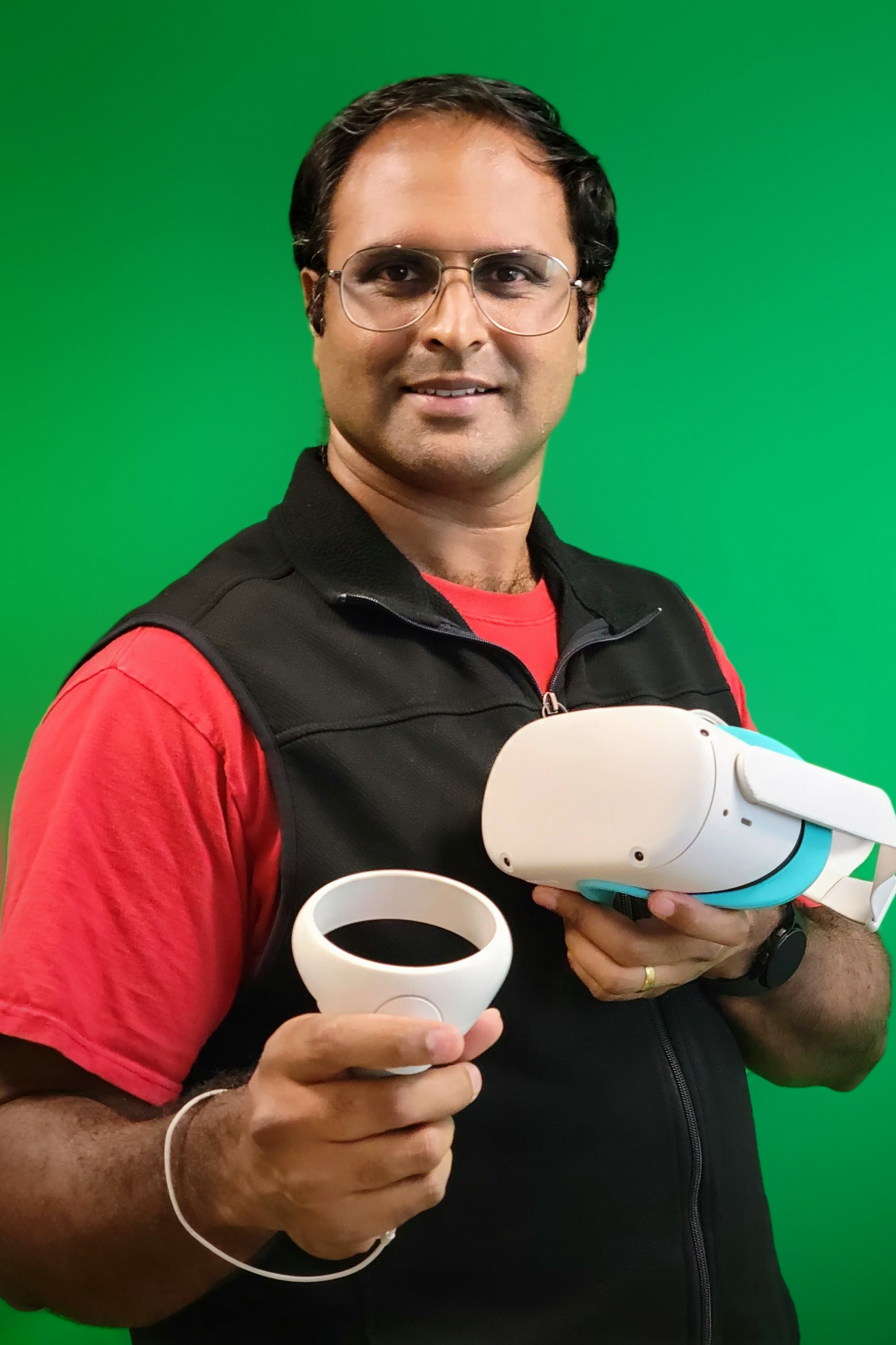 Arun Ramakrishnan, Director of Research Labs, standing in front of a green screen and holding virtual reality googles.